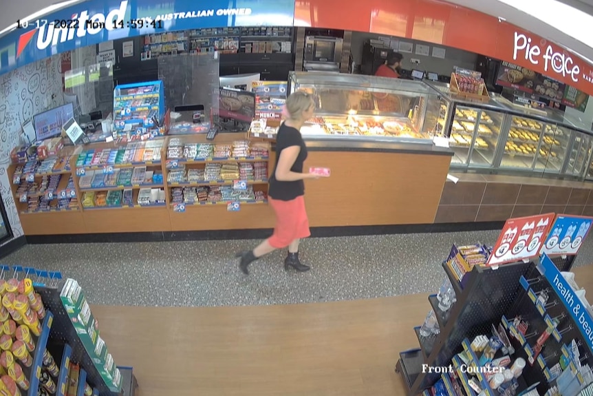 Ein Screenshot einer CCTV-Vision einer blonden Frau, die in der Nähe des Schalters einer Tankstelle entlanggeht