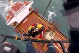 A man is winched down onto a ship