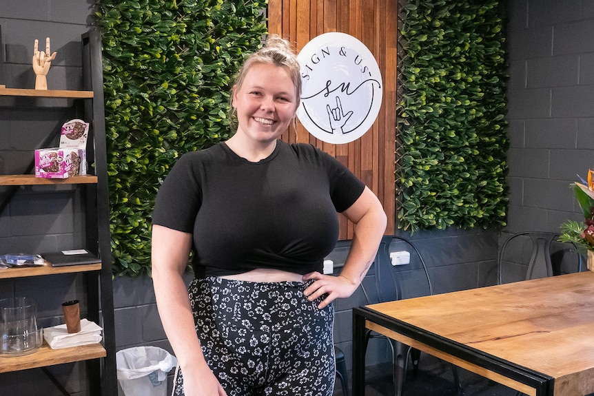 A woman wearing gym clothes smiles a for photo inside a gym.