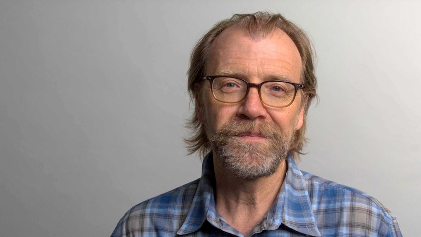 Author George Saunders, a man in his 60s in glasses, beard and blue checked shirt