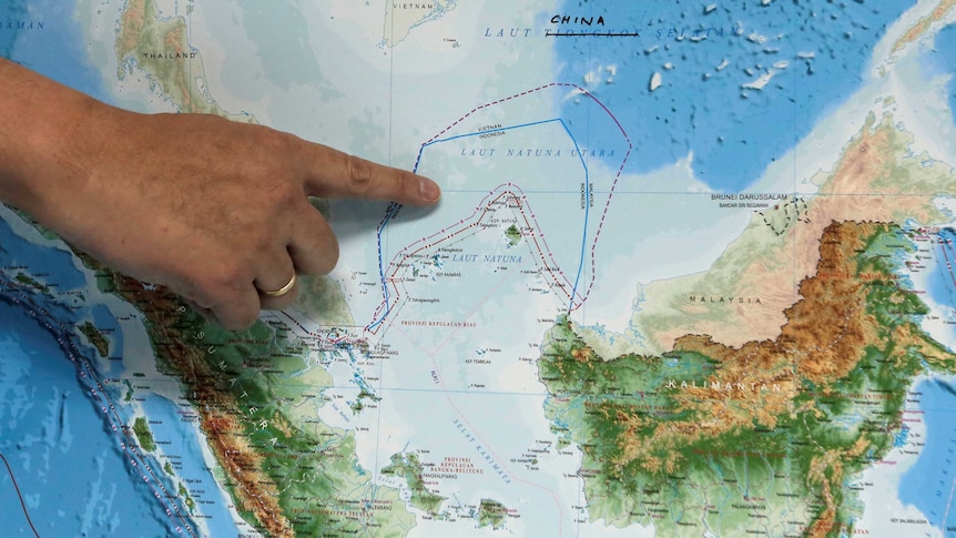 A finger points to the North Natuna Sea on a map of Southeast Asia.