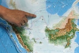 A finger points to the North Natuna Sea on a map of Southeast Asia.