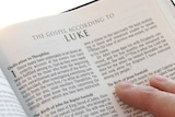 A person's hand holding open a Bible