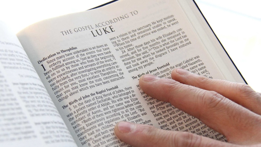 A person's hand holding open a Bible