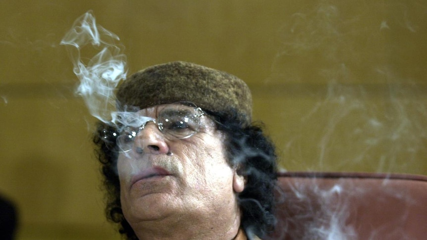 Libyan leader Gaddafi smokes a cigarette