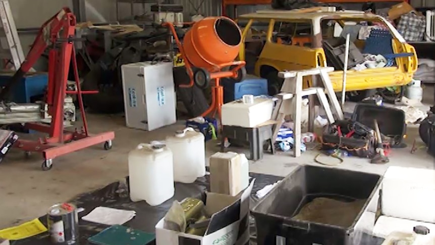 Garage containing mini cement mixer with plastic containers of chemicals and plant material