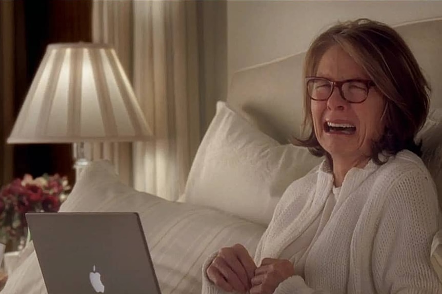 Diane Keaton sobbing at a laptop in bed.