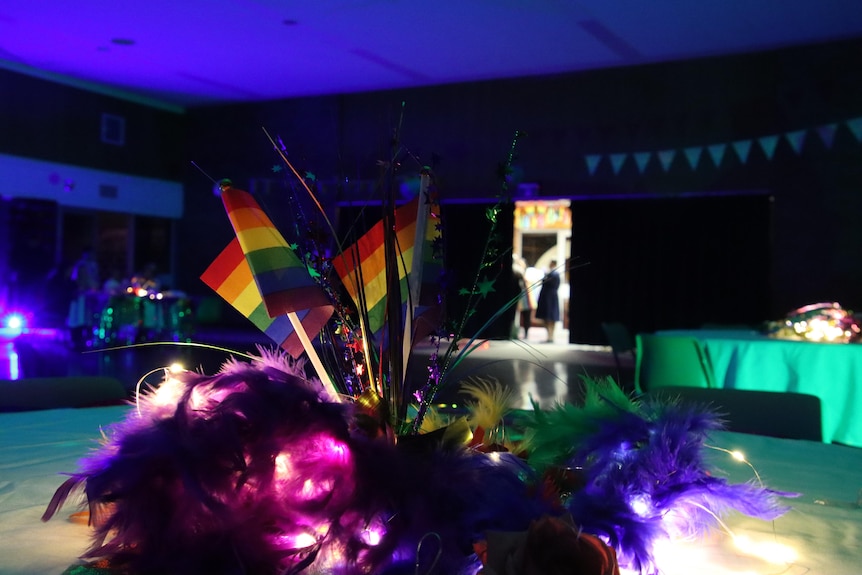 Rainbow flags on a table setting in rainbow lights. 