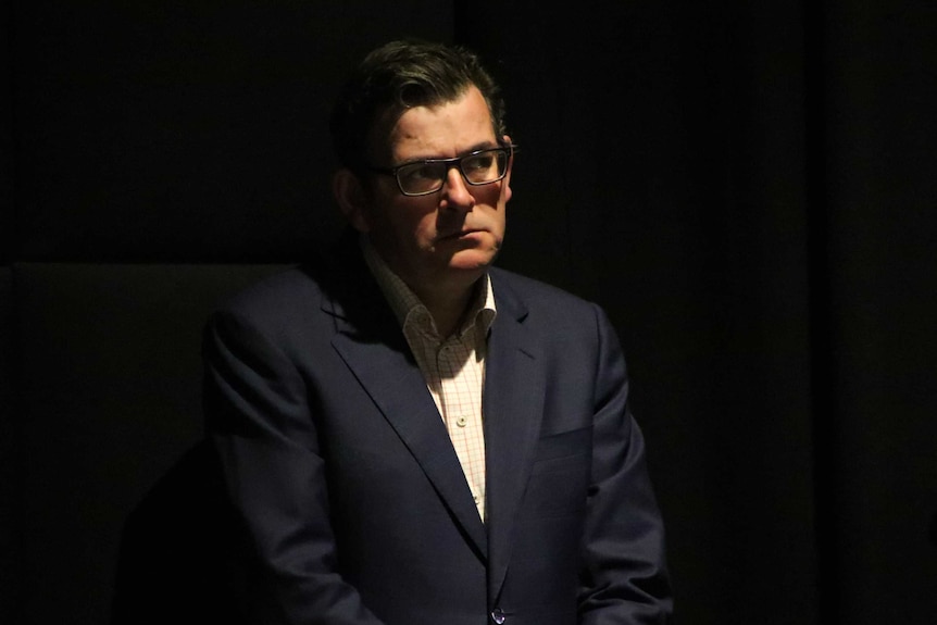 Victorian Premier Daniel Andrews stands half in shadow