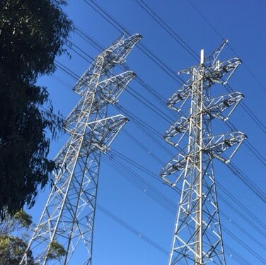 Two electricity towers against blue sky.