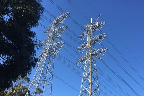 Two electricity towers against blue sky.