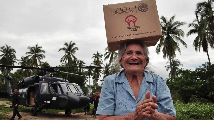 Residents help unload humanitarian aid from a Black Hawk helicopter.