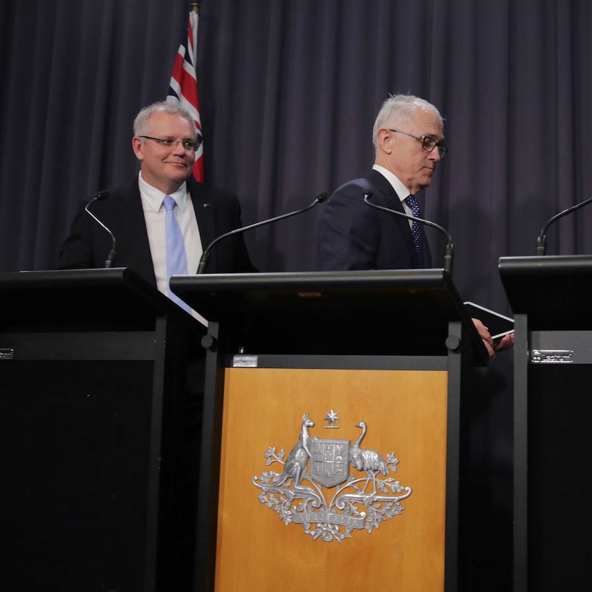 Malcolm Turnbull and Josh Frydenberg walk away from their podiums as Scott Morrison stands at his.