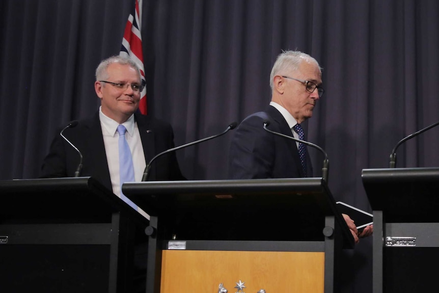 Malcolm Turnbull and Josh Frydenberg walk away from their podiums as Scott Morrison stands at his.