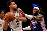 Ben Simmons holds the ball under defensive pressure from Montrezl Harrell
