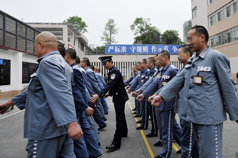 Chinese prisoners exercising in jail on the playground.