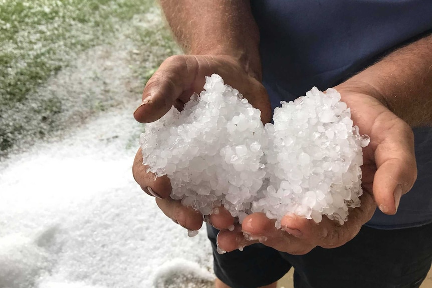 A man holds a pile of hail in his hands