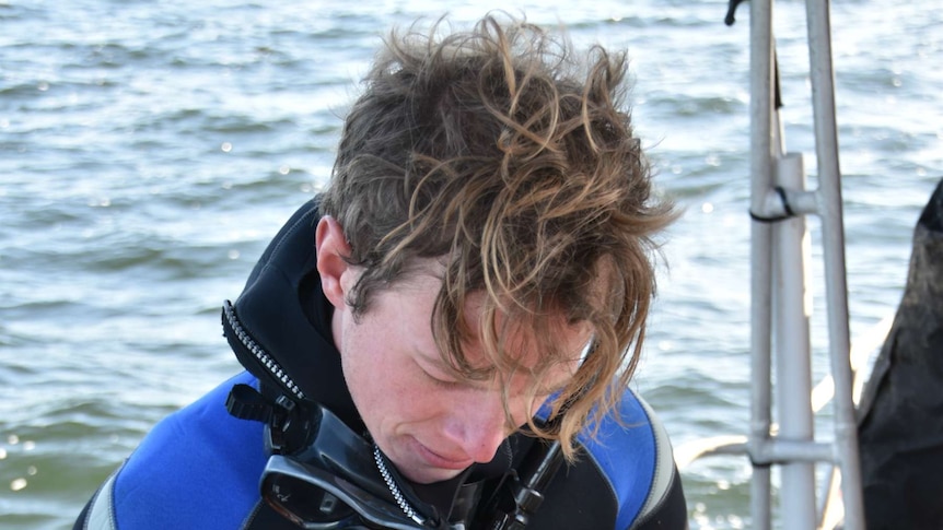 Bryn Warnock in a wetsuit prepares to place shellfish on to the sea bed.