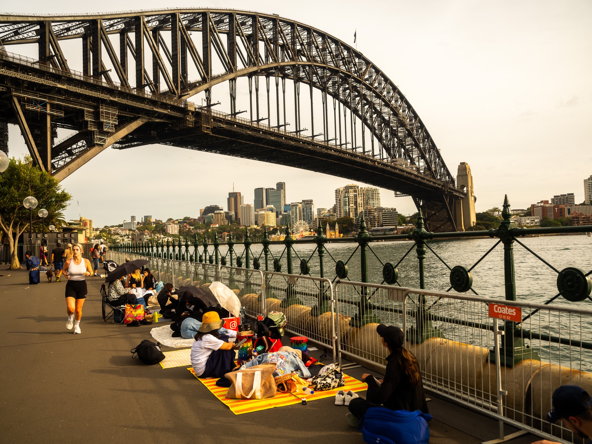 La gente se sienta sobre mantas frente al puente del puerto de Sydney.