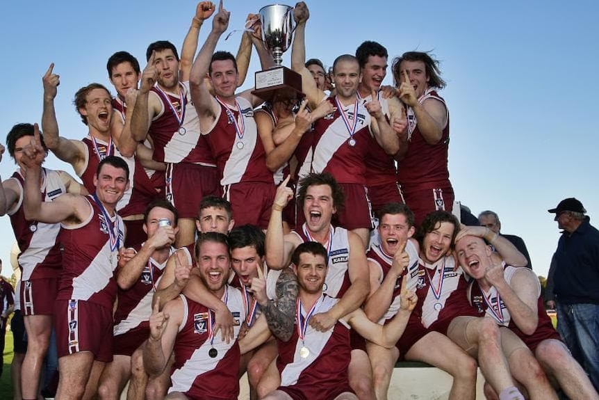 A footbal team celebrates after winning a grand final.