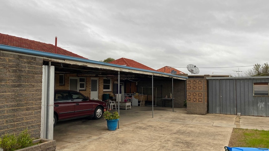 The back of a house with a car under a verandah.