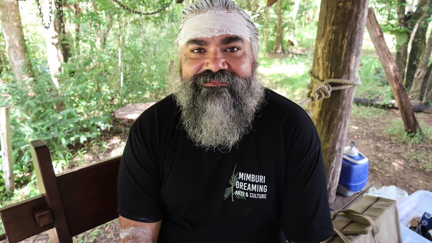 A man in a black shirt with a bushy beard and some traditional face paint.