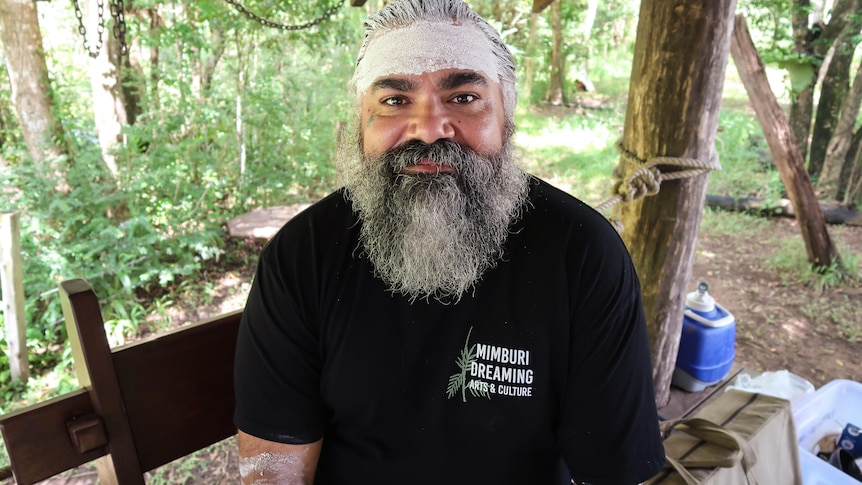 A man in a black shirt with a bushy beard and some traditional face paint.
