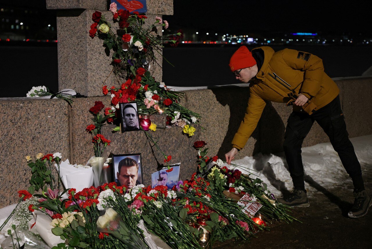 A man lays a flower near a shrine 