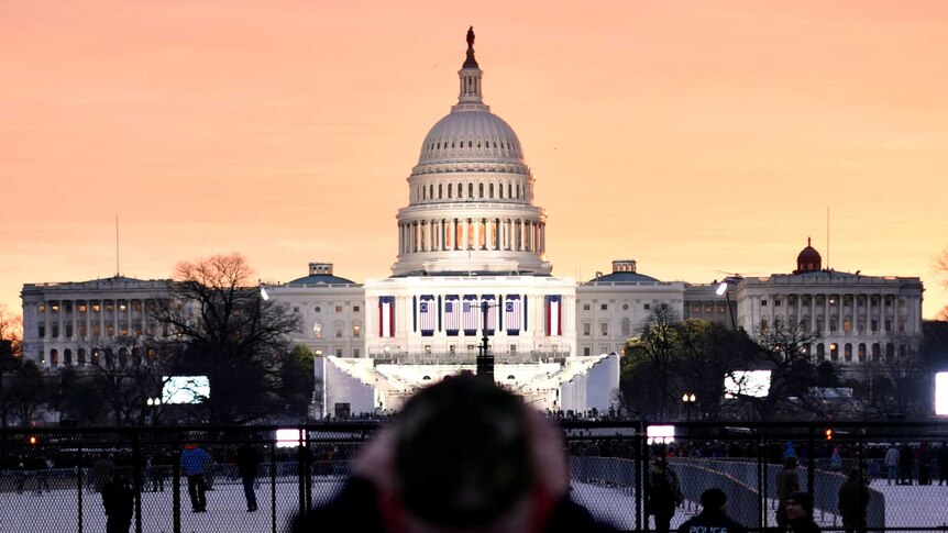 A Trump supporter photographs the US Capitol as the sun rises on the National Mall