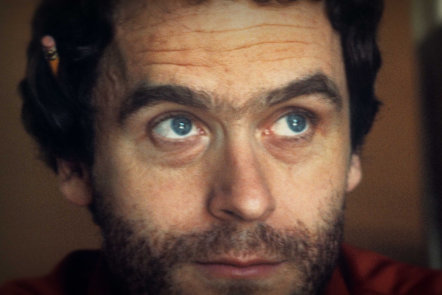 A close-up portrait of American serial killer Ted Bundy, showing his thick eyebrows and blue eyes.