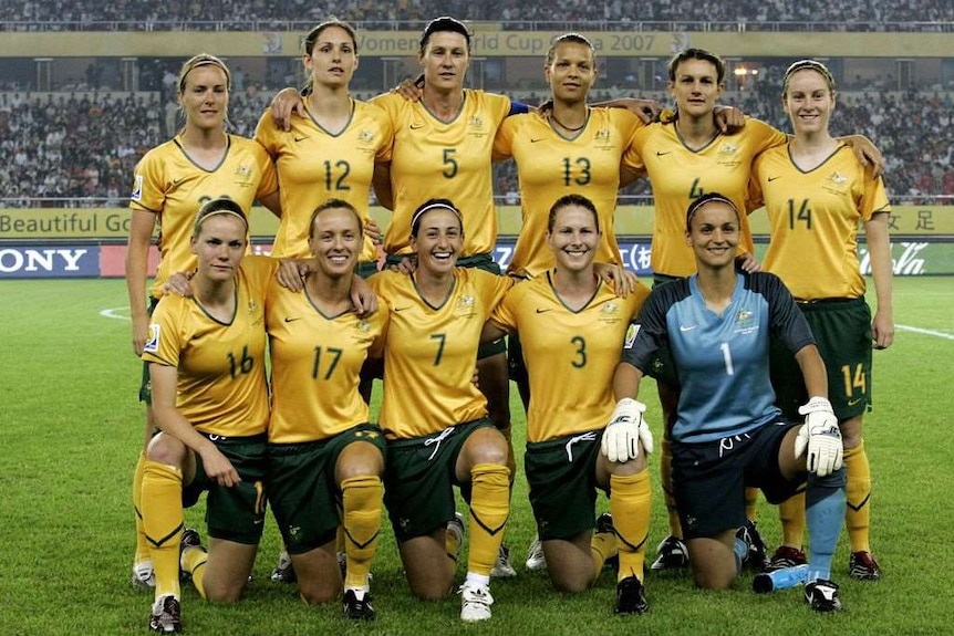 A women's soccer team wearing yellow and green poses for a photo before a big game