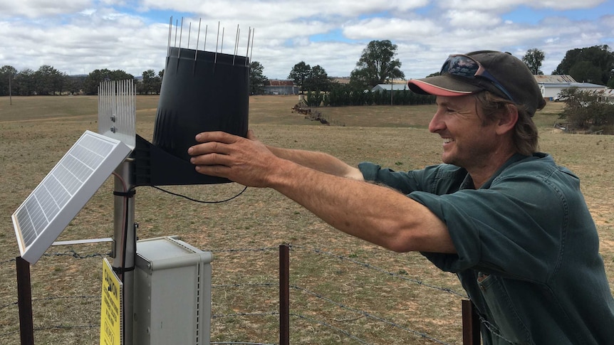 A smiling man holding a soil moisture probe on a farm