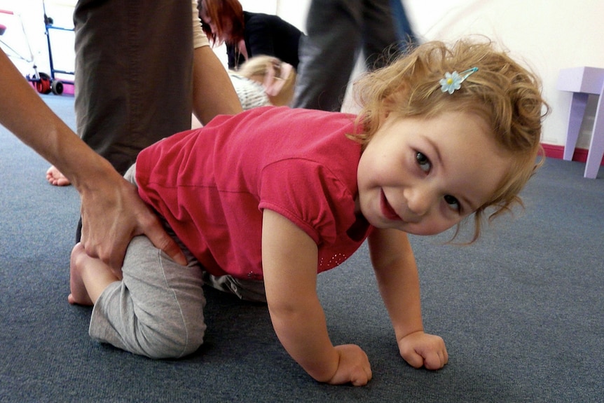 Two-year-old Chloe Brown learns to crawl as part of her first conductive education class.
