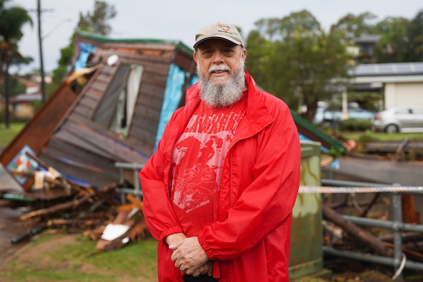 neighbour in red clothes standing in front of destroyed brown-clad granny flat