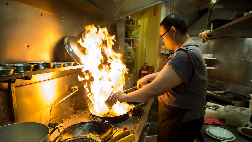 A cook prepares food over the wok at Happy's Chinese restaurant in Canberra.
