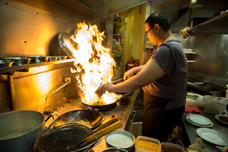 A cook prepares food over the wok at Happy's Chinese restaurant in Canberra.