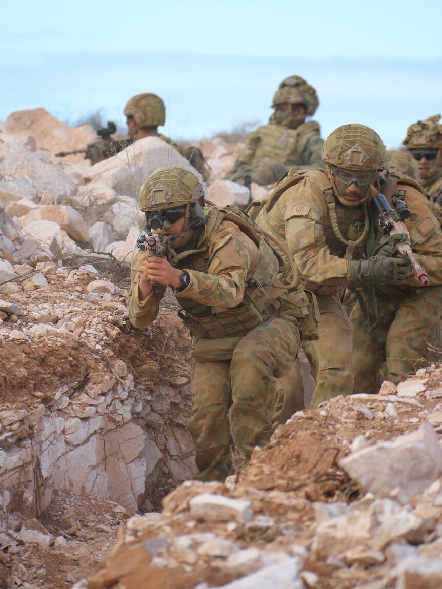 Soldiers clear an enemy trench during training.