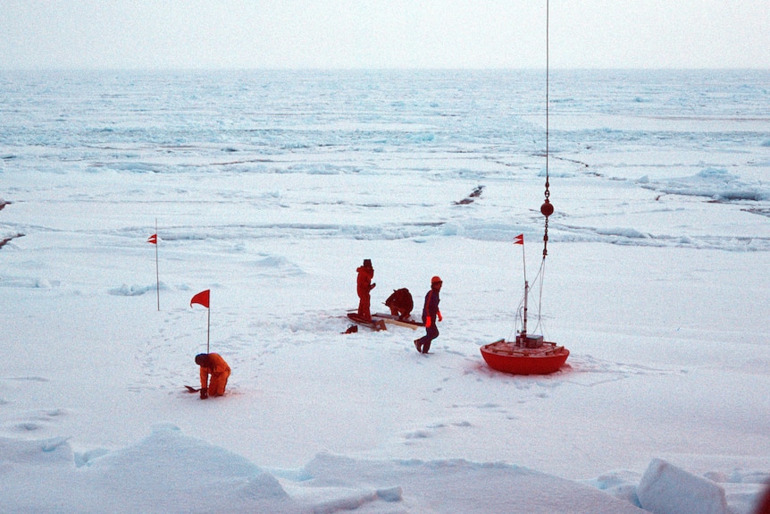 A team of scientist deploying research intruments onto a vast sea ice field in Antarctica