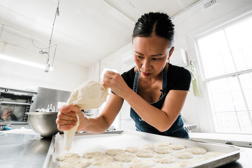 A woman with a focussed expression uses a piping bag.