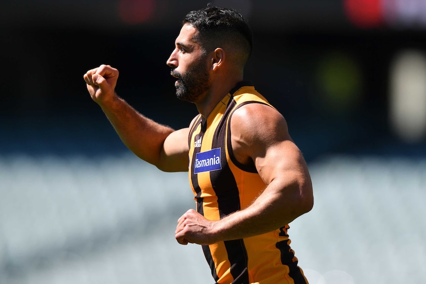 A Hawthorn AFL player holds up his right hand in the shape of a fist as he celebrates a goal against Gold Coast.