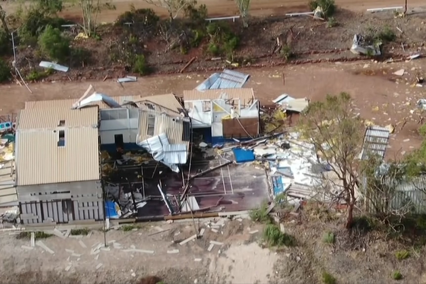An aerial photo of a house destroyed by a cyclone, with debris strewn across the ground.