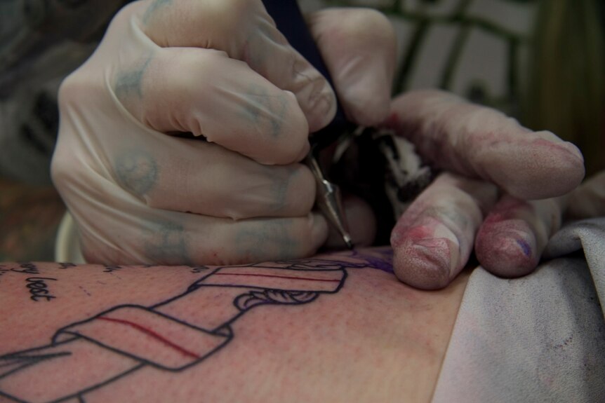 A tattoo needle presses down on skin.