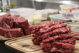 Piles of highly marbled steak. One is diced and skewered, and one is fist sized lumps.