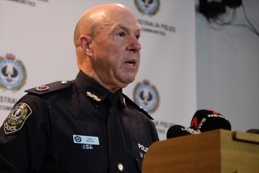 A man in police uniform speaking into microphones at a reading