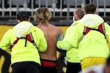 Four secuity guards in yellow hi-vis jackets and face masks escort a pitch invader off Perth Stadium with an umpire nearby.