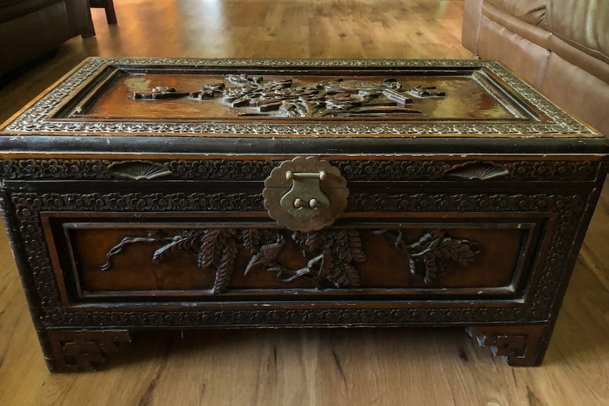 A wooden box with a large brass latch on the front.