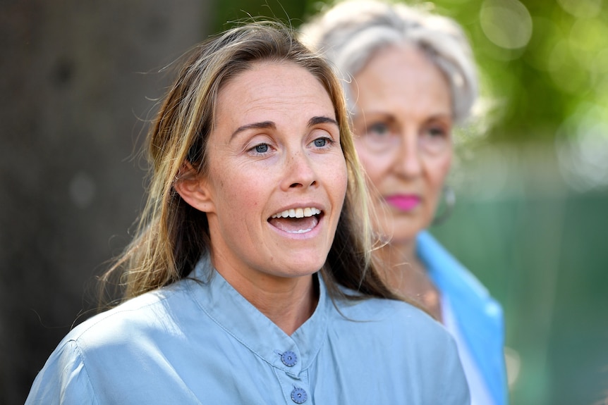 Woman in blue talking to media