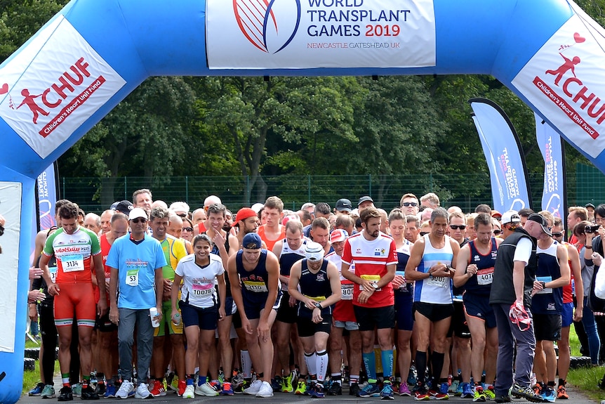 A large group of people gather at the start line of a running race. 