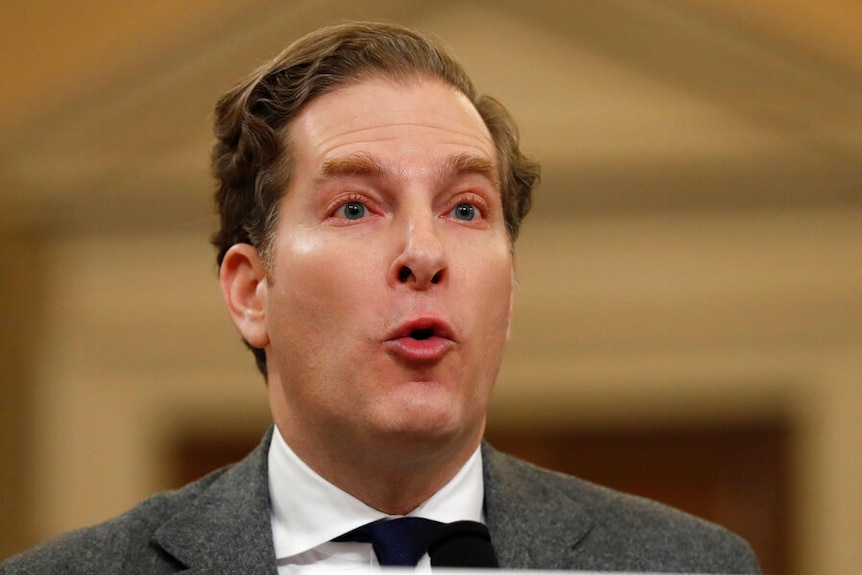 Noah Feldman has his lips pursed as he speaks on top of a desk at an impeachment hearing.