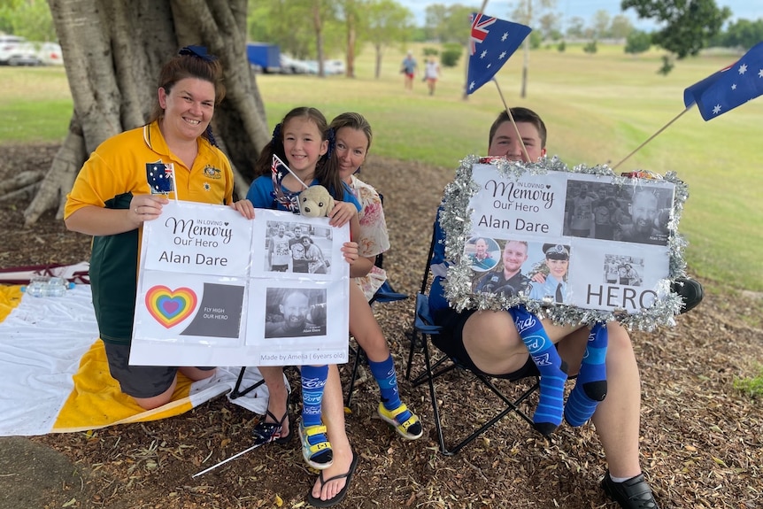 The family of four holding signs calling Allan Dare a hero. 